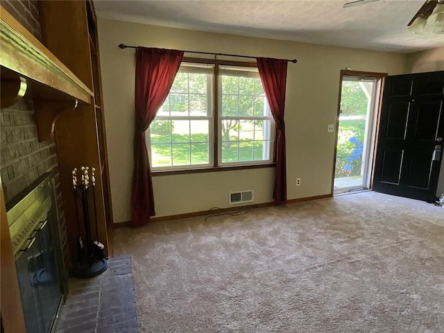 unfurnished living room with ceiling fan, carpet flooring, and a fireplace