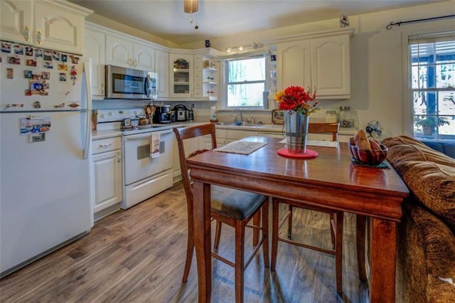 kitchen with sink, white appliances, light wood-type flooring, ceiling fan, and white cabinets