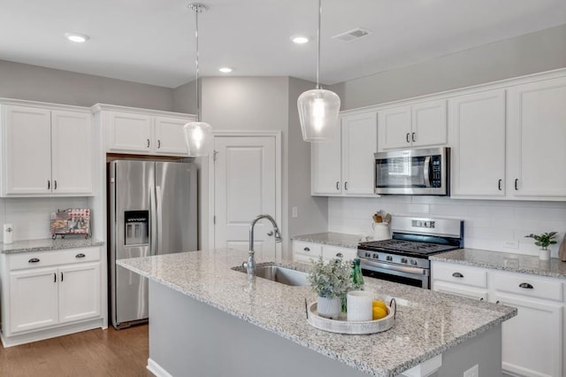 kitchen with visible vents, wood finished floors, stainless steel appliances, white cabinetry, and a sink