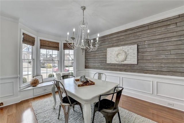 dining space with ornamental molding, a chandelier, and light wood-type flooring