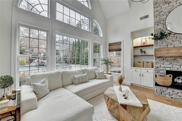 living room with light wood-type flooring, a healthy amount of sunlight, and a high ceiling