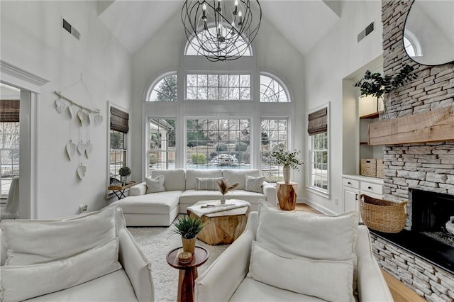 living room with an inviting chandelier, a fireplace, high vaulted ceiling, and wood-type flooring