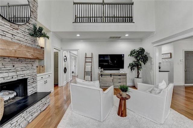 living room with a fireplace, light hardwood / wood-style flooring, and a high ceiling