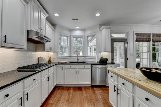 kitchen featuring butcher block countertops, sink, light hardwood / wood-style flooring, appliances with stainless steel finishes, and white cabinets