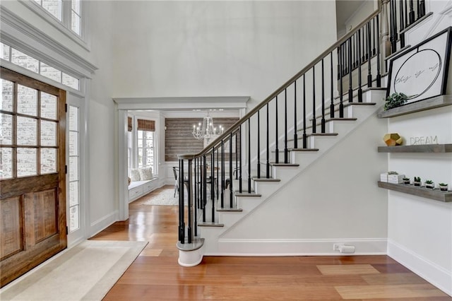 foyer featuring a notable chandelier, hardwood / wood-style flooring, and a towering ceiling