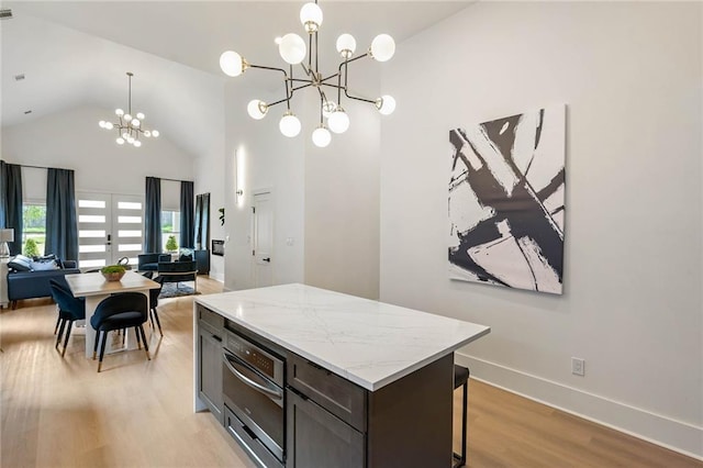 kitchen featuring a kitchen island, light wood-style flooring, hanging light fixtures, a notable chandelier, and open floor plan