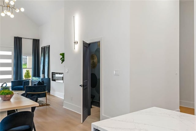 bedroom featuring a notable chandelier, light wood-style flooring, and high vaulted ceiling