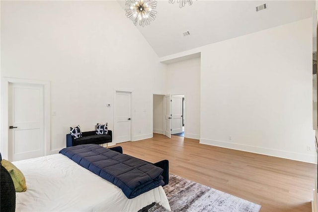 bedroom with visible vents, baseboards, light wood-style flooring, an inviting chandelier, and high vaulted ceiling