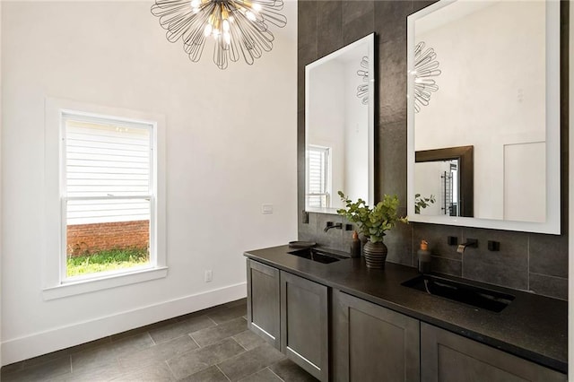 bar featuring an inviting chandelier, baseboards, backsplash, and a sink