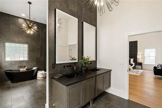 ensuite bathroom featuring tile walls, an inviting chandelier, and a sink