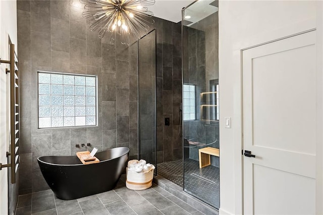 full bathroom featuring tile patterned flooring, a chandelier, a freestanding bath, a stall shower, and tile walls