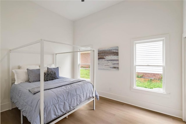 bedroom featuring multiple windows, baseboards, and wood finished floors