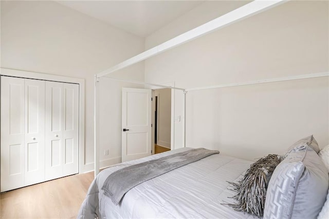 bedroom featuring lofted ceiling, wood finished floors, and a closet