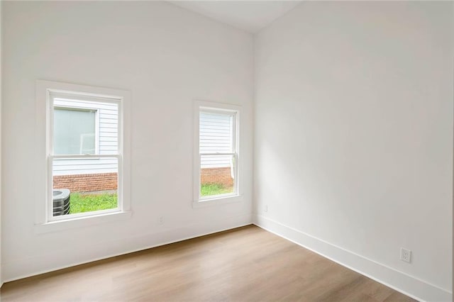 spare room with baseboards and wood finished floors