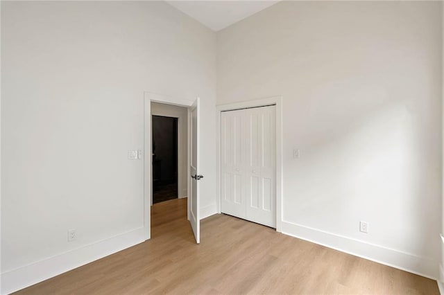 unfurnished bedroom with a closet, light wood-style flooring, and baseboards