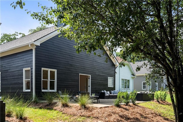 back of property featuring a patio area, an outdoor hangout area, and a shingled roof