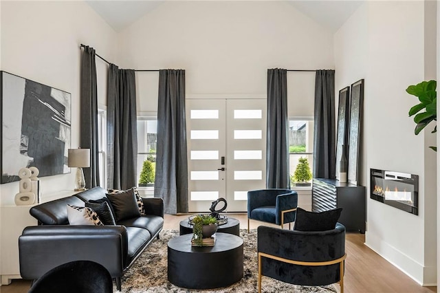 living area with wood finished floors, baseboards, french doors, and high vaulted ceiling