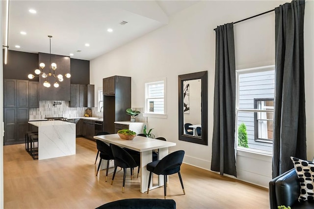 dining space featuring recessed lighting, a notable chandelier, light wood-style flooring, and baseboards