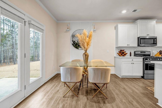 dining room with crown molding, light wood-type flooring, and a wealth of natural light