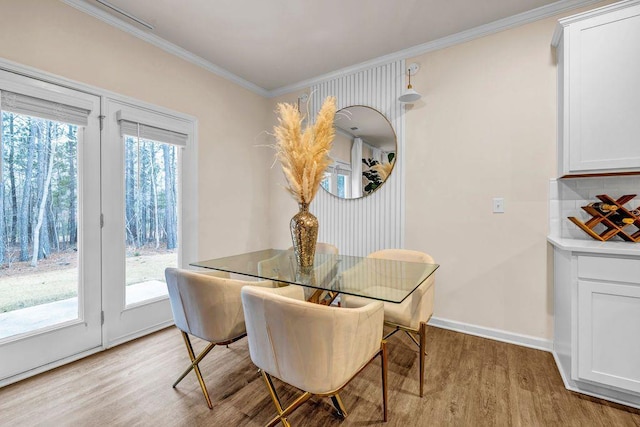 dining space featuring light wood-type flooring and ornamental molding