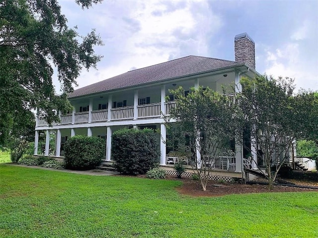 back of property with a balcony and a yard