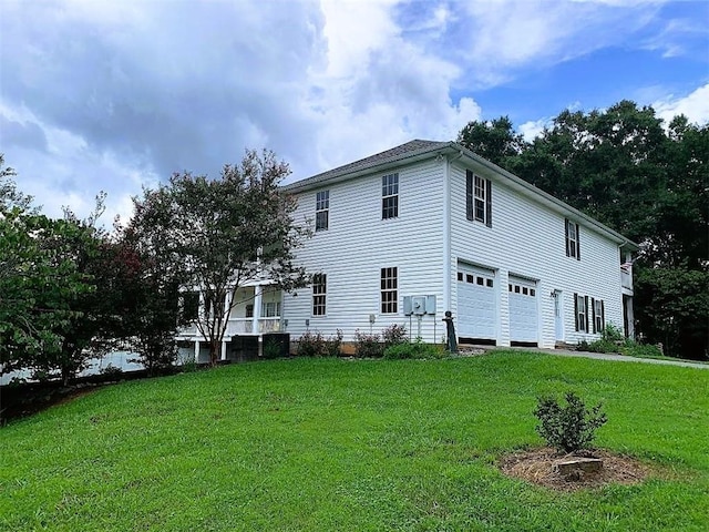 rear view of property featuring a yard, central air condition unit, and a garage