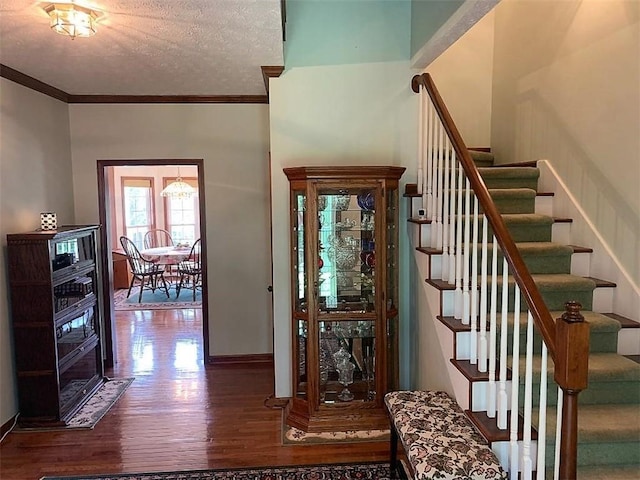 staircase featuring dark hardwood / wood-style floors, a textured ceiling, and ornamental molding