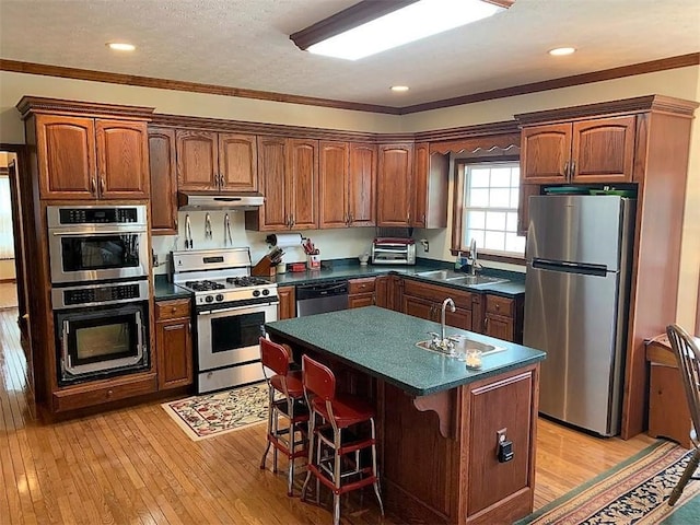 kitchen with a center island with sink, stainless steel appliances, light hardwood / wood-style flooring, and sink