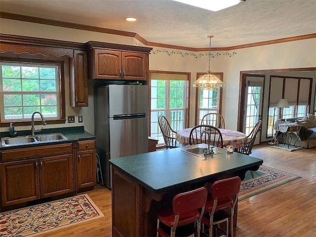 kitchen featuring a chandelier, ornamental molding, light hardwood / wood-style flooring, stainless steel refrigerator, and sink