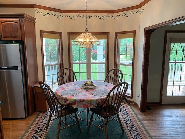 dining room with an inviting chandelier, light wood-type flooring, ornamental molding, and a wealth of natural light