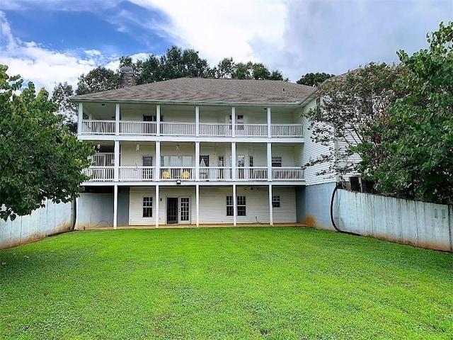 rear view of house with a balcony and a lawn