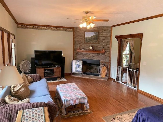 living room with ornamental molding, ceiling fan, dark hardwood / wood-style floors, and a fireplace