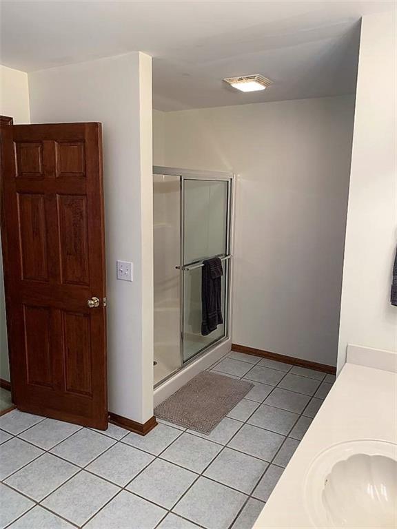 bathroom featuring an enclosed shower, tile flooring, and sink