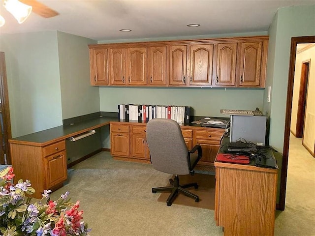 carpeted home office with ceiling fan and built in desk