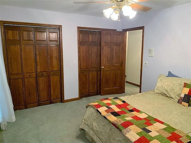 bedroom with light colored carpet, two closets, and ceiling fan