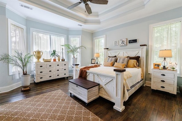 bedroom featuring ornamental molding, visible vents, dark wood finished floors, and a raised ceiling