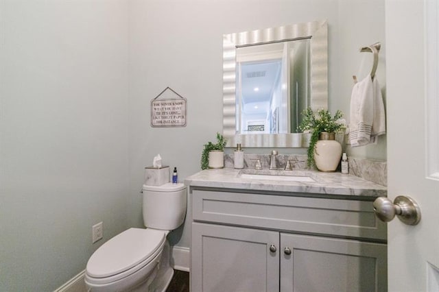 half bathroom featuring baseboards, vanity, and toilet