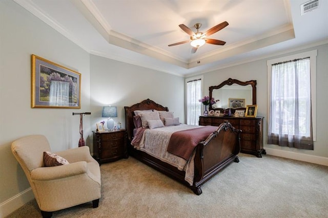 bedroom with a tray ceiling, crown molding, visible vents, light carpet, and baseboards