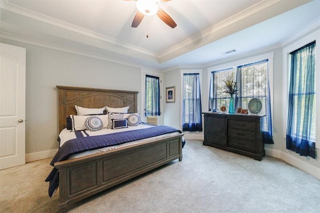 bedroom with a tray ceiling, light colored carpet, visible vents, ornamental molding, and baseboards