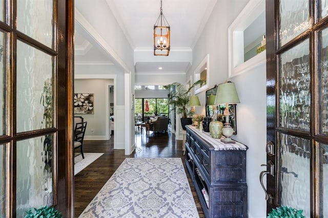 entrance foyer with crown molding, dark wood finished floors, baseboards, and an inviting chandelier