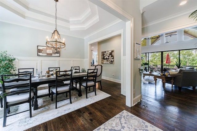 dining space with a notable chandelier, a decorative wall, dark wood-type flooring, wainscoting, and crown molding