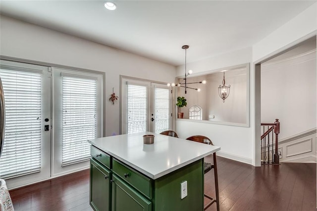 kitchen featuring dark wood-style floors, a breakfast bar area, an inviting chandelier, a kitchen island, and green cabinetry