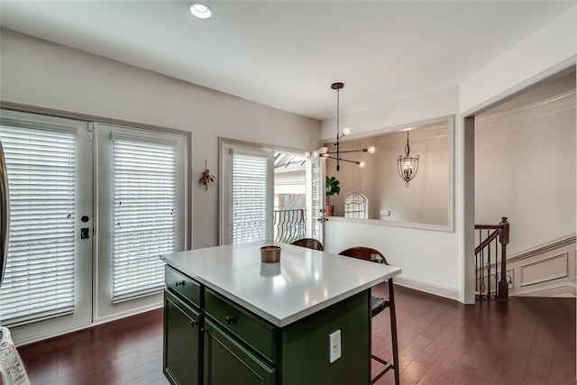 kitchen with dark wood-style flooring, green cabinetry, a notable chandelier, and a kitchen breakfast bar