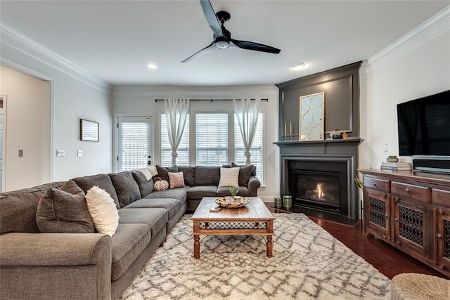 living area with ceiling fan, recessed lighting, dark wood-style floors, a glass covered fireplace, and crown molding