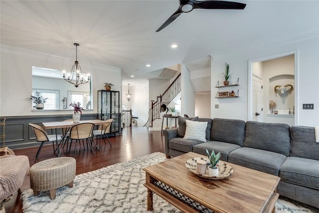 living room featuring ceiling fan with notable chandelier, stairway, crown molding, and wood finished floors