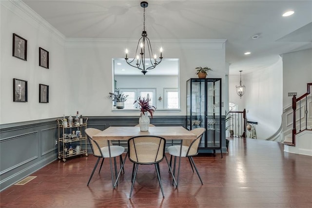 dining space with dark wood-style flooring, crown molding, a notable chandelier, visible vents, and stairs