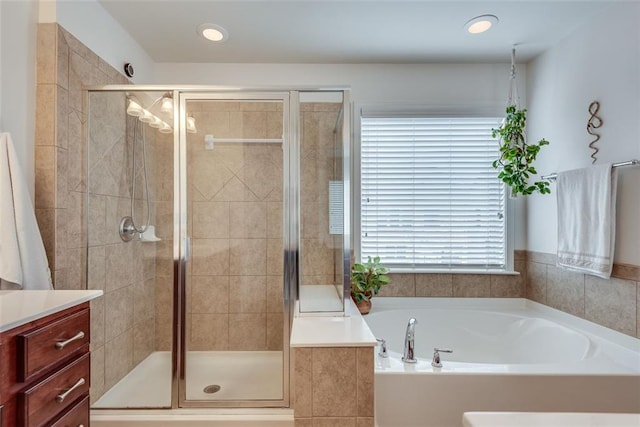 bathroom with a shower stall, vanity, and a bath