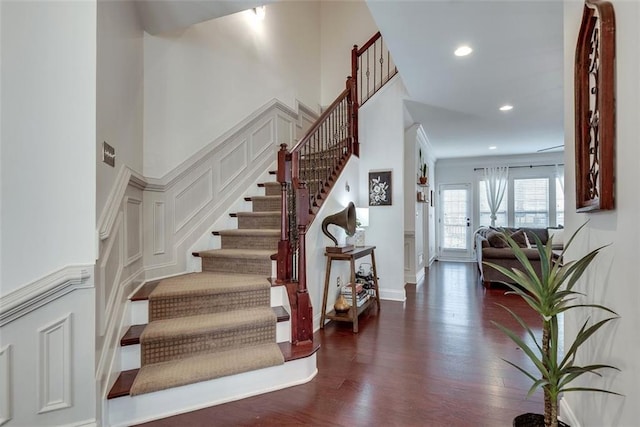 stairway featuring recessed lighting, baseboards, a high ceiling, and wood finished floors