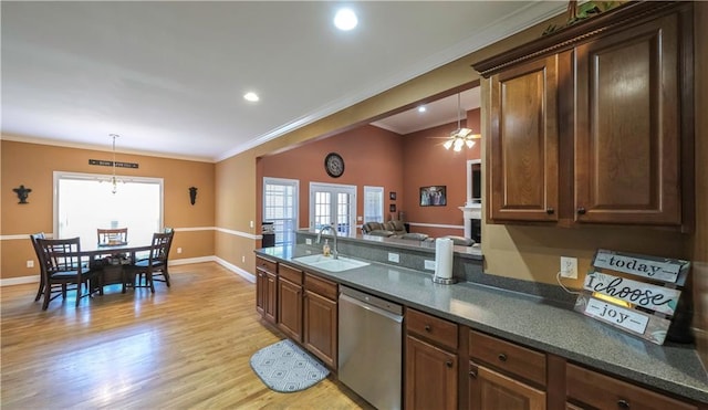 kitchen featuring dark countertops, dishwasher, light wood-type flooring, and a sink