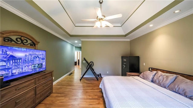 bedroom with recessed lighting, baseboards, light wood-type flooring, a raised ceiling, and crown molding